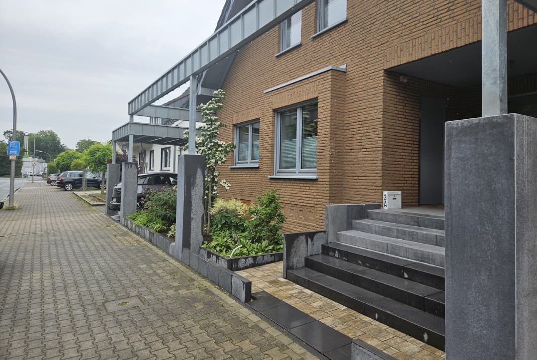 Gepflasterter Eingangsbereich mit Natursteintreppe vor Mehrfamilienhaus