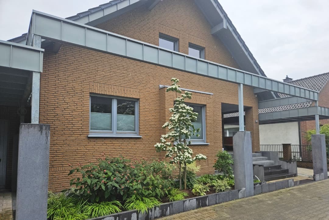 Backsteinhaus mit gepflasterter Auffahrt und blühendem Zierbaum